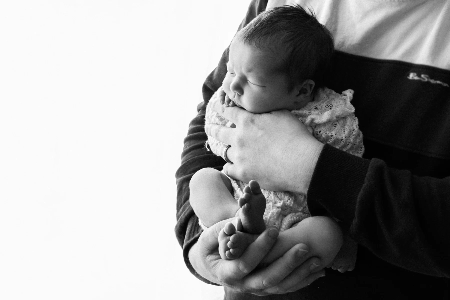 Parent cradling a newborn baby in monochrome
