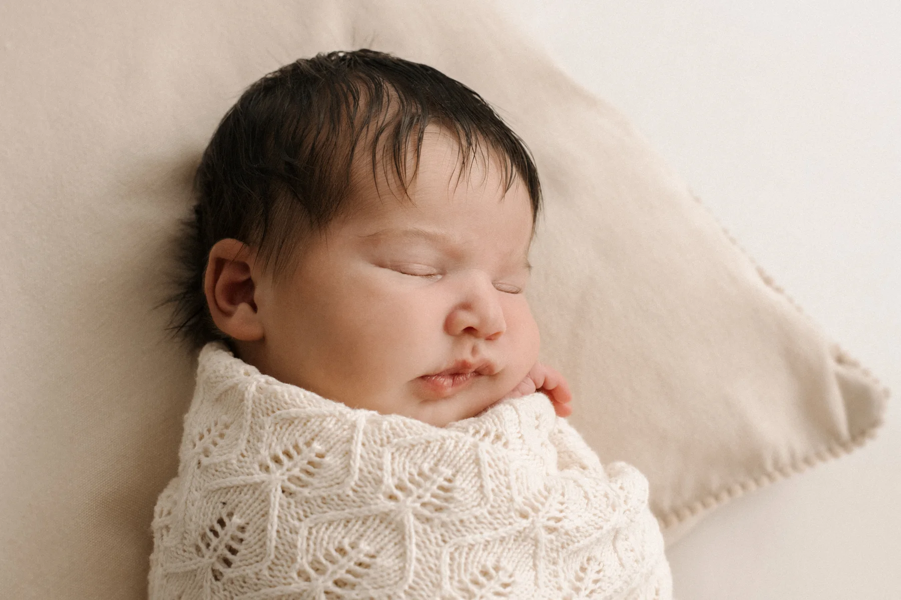 Sleeping newborn in a neutral knitted wrap