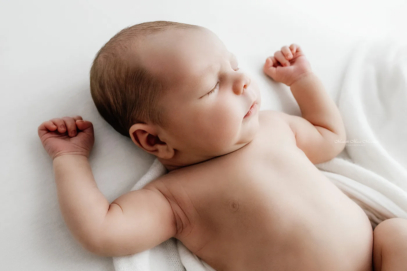 Newborn asleep on light linen
